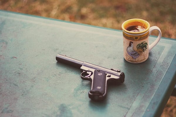 a gun on a table beside a cup of tea
