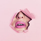 Mouth with pink lipstick breaking through pink paper